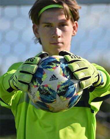 A young man holding a soccer ball in his hands.