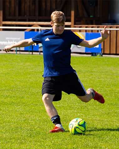 A man kicking around a soccer ball on the field.