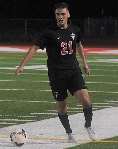 A soccer player in black uniform on the field.