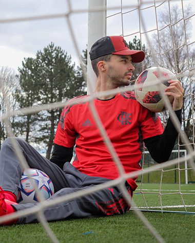 A man sitting on the ground holding a soccer ball.