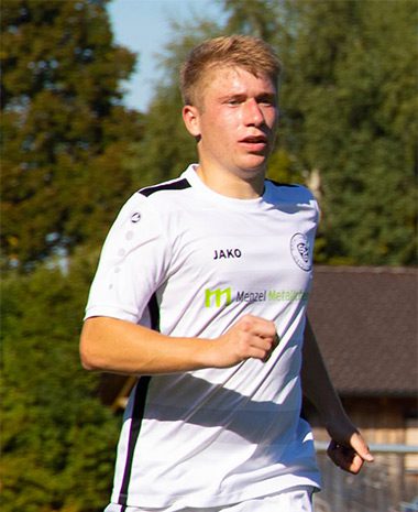 A young man running on the field wearing white.