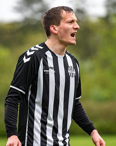 A soccer player in black and white striped shirt.