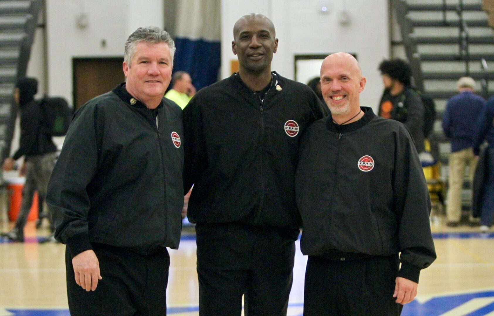 Three men in black jackets standing next to each other.